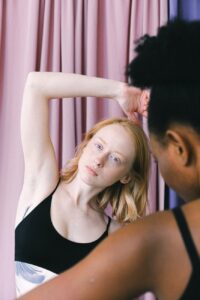 woman in black sports bra stretching with arm raised